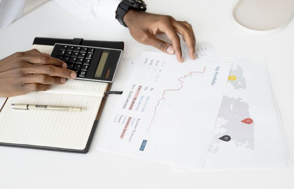 Overhead view of a person analyzing financial documents using a calculator for investment planning.